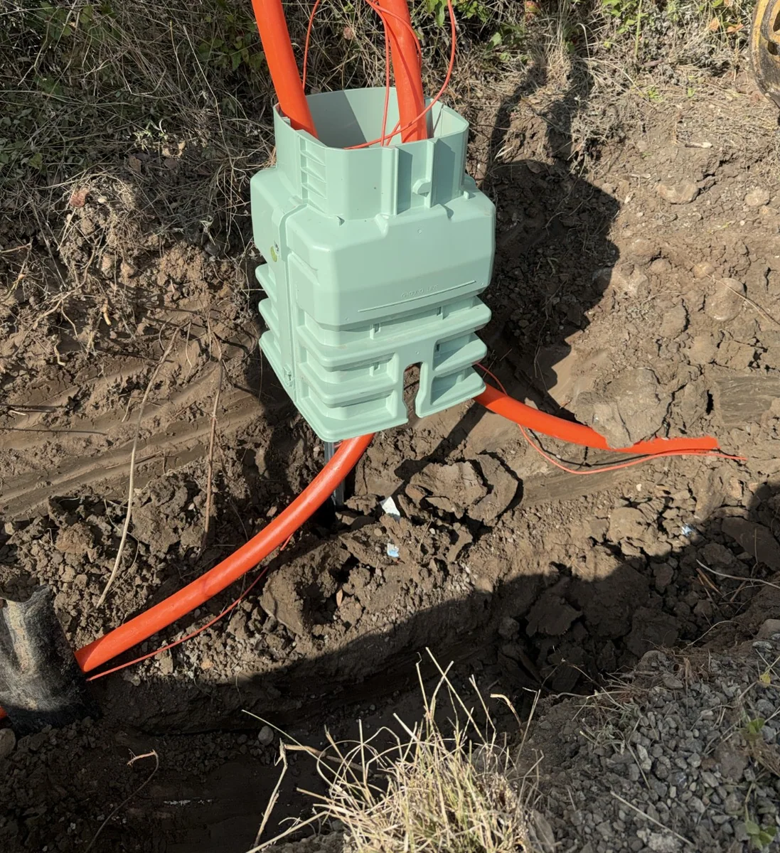 Utility pedestal base with orange conduit connections